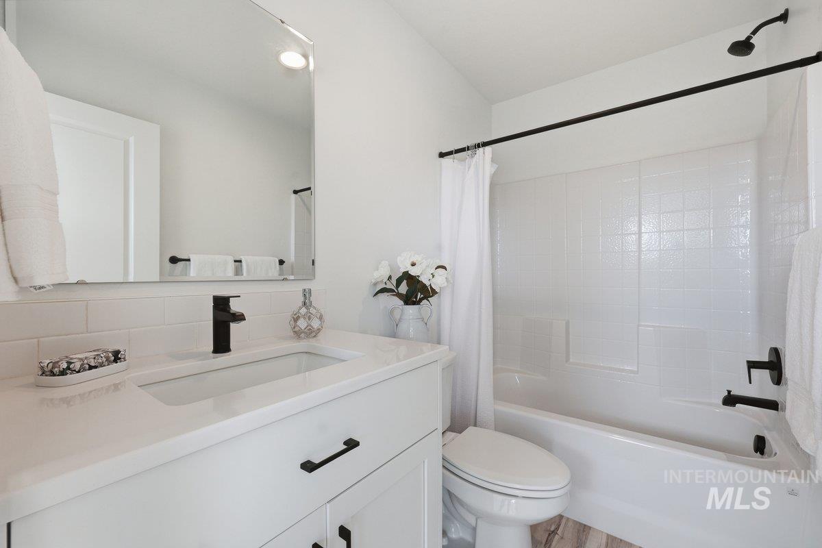 Full bath with vanity, shower / bathtub combination with curtain, and tasteful backsplash