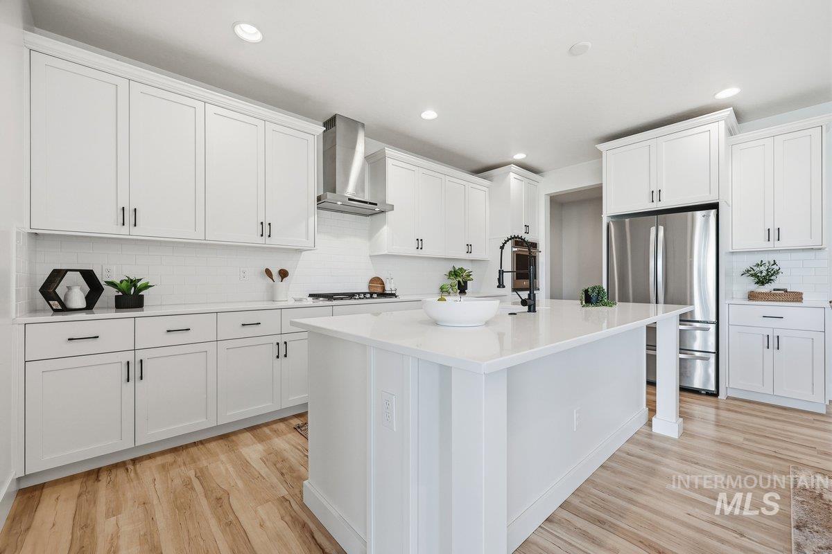 Kitchen with decorative backsplash, freestanding refrigerator, light wood-style floors, white cabinets, and recessed lighting