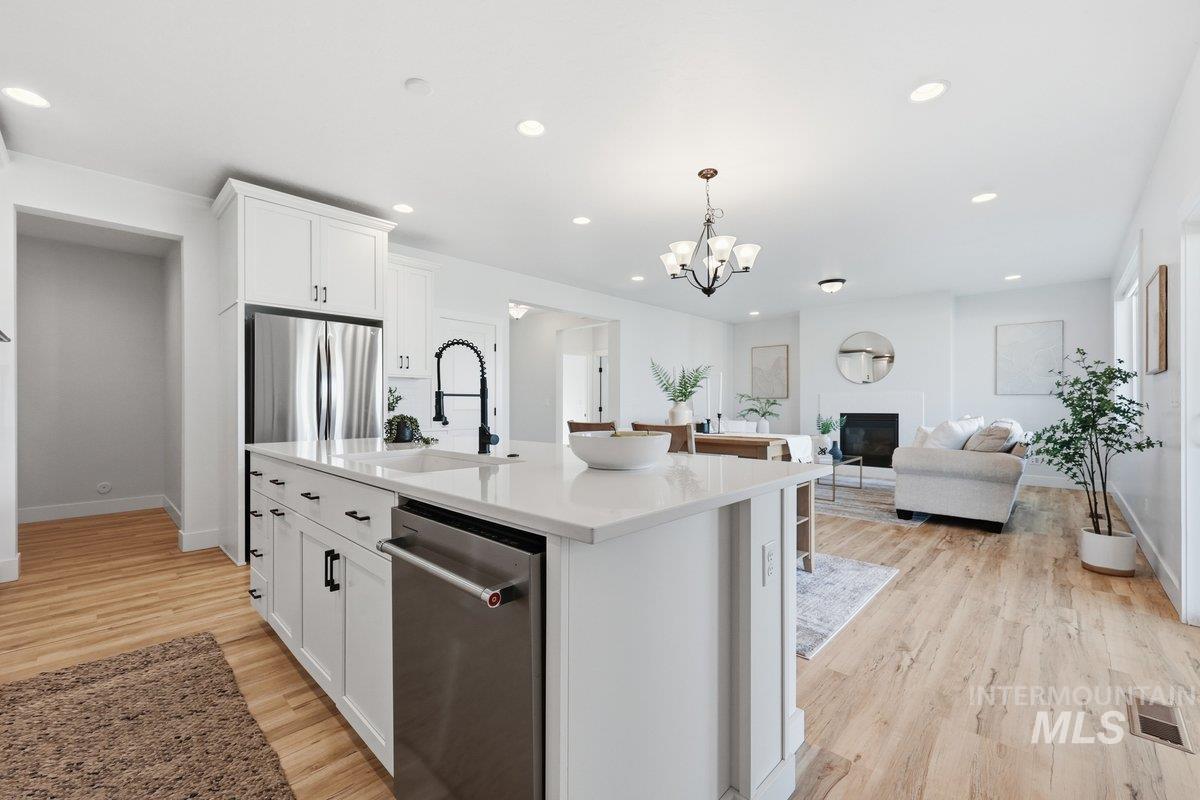 Kitchen with white cabinets, hanging light fixtures, appliances with stainless steel finishes, open floor plan, and recessed lighting