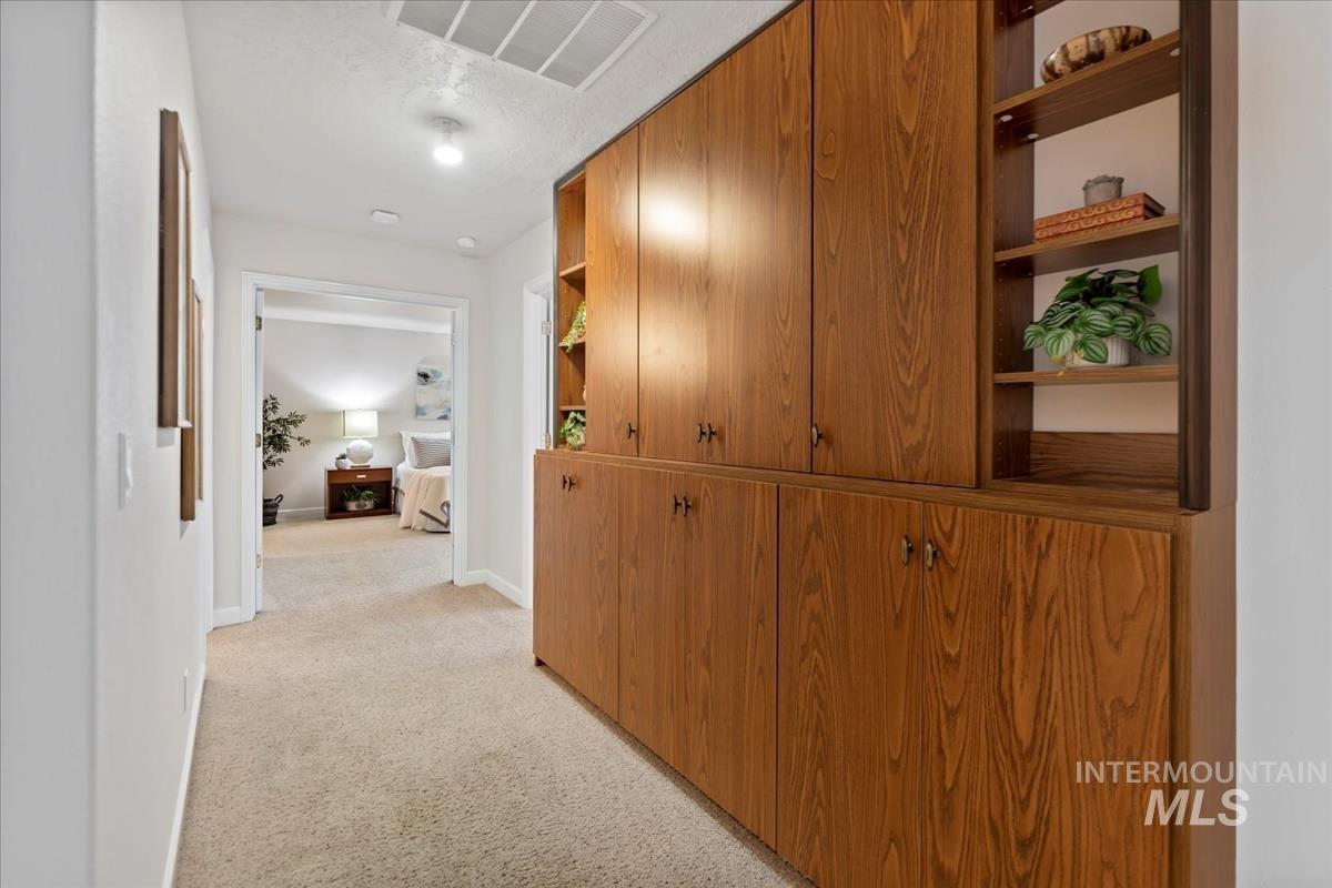 Hallway featuring light colored carpet and baseboards