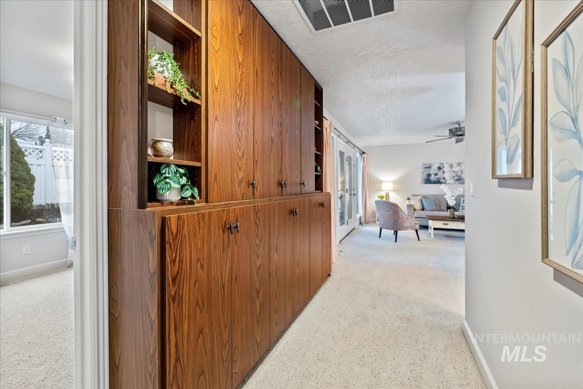 Hallway with light colored carpet and baseboards