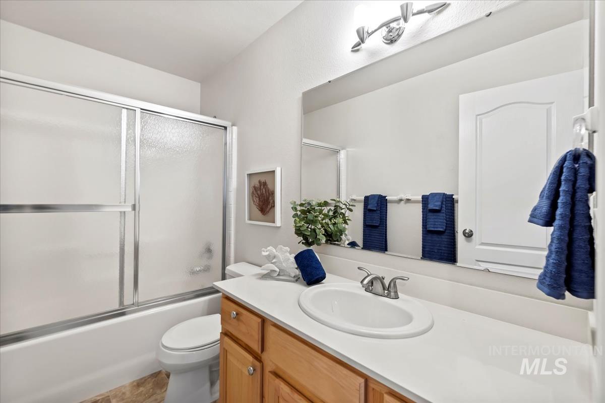 Bathroom featuring vanity and shower / bath combination with glass door