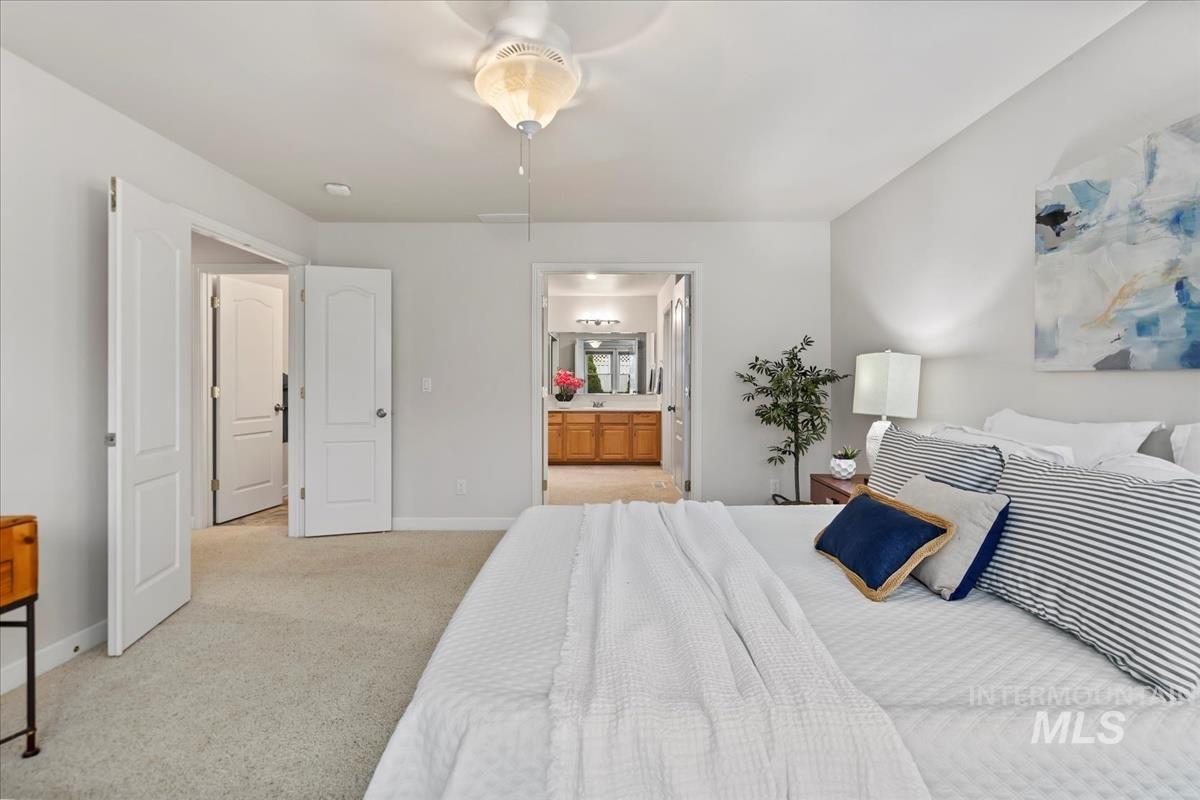 Bedroom featuring light carpet, connected bathroom, and ceiling fan