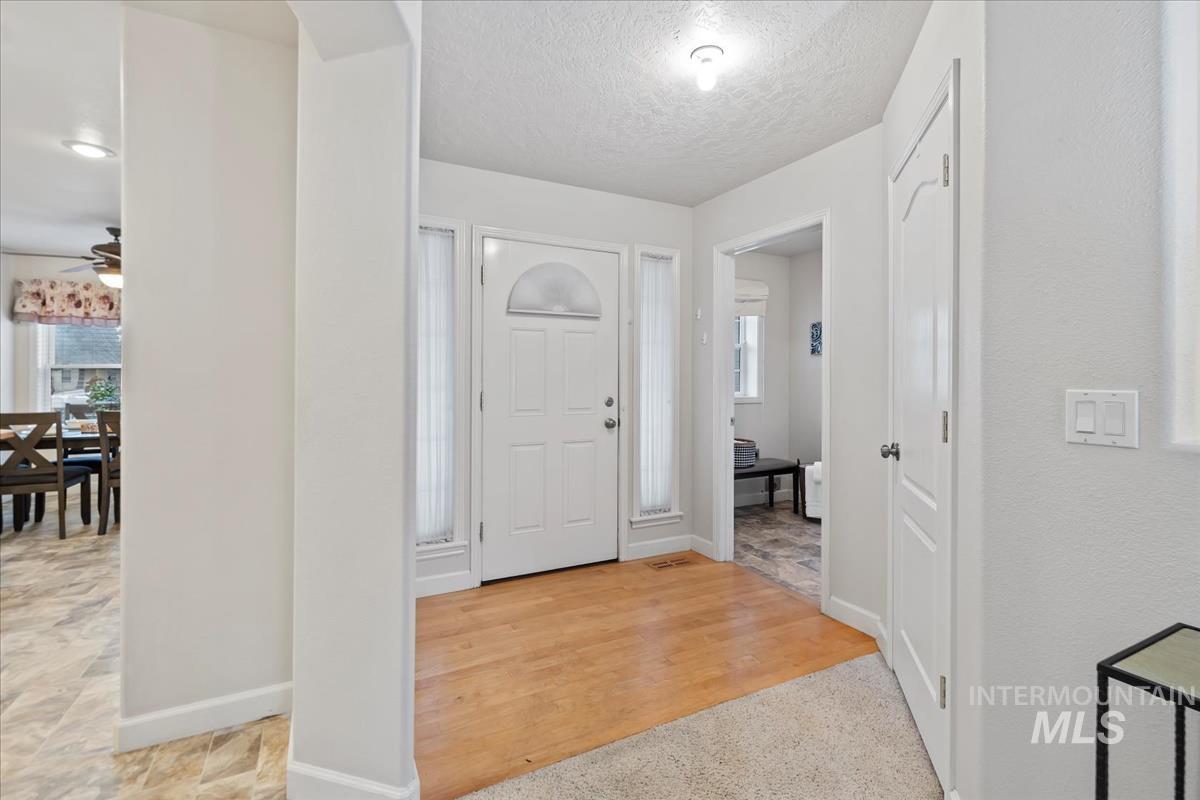 Entrance foyer with light wood-style floors and a textured ceiling