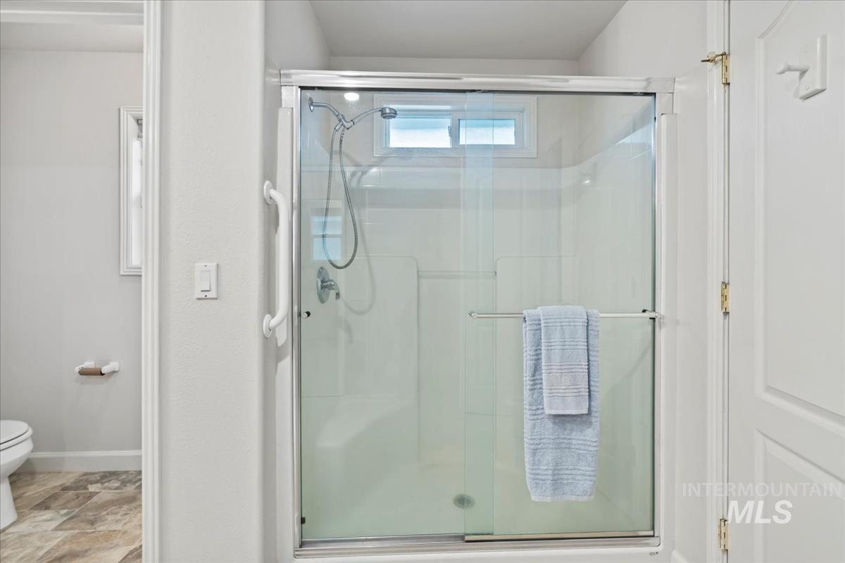 Bathroom featuring a stall shower and stone finish floors