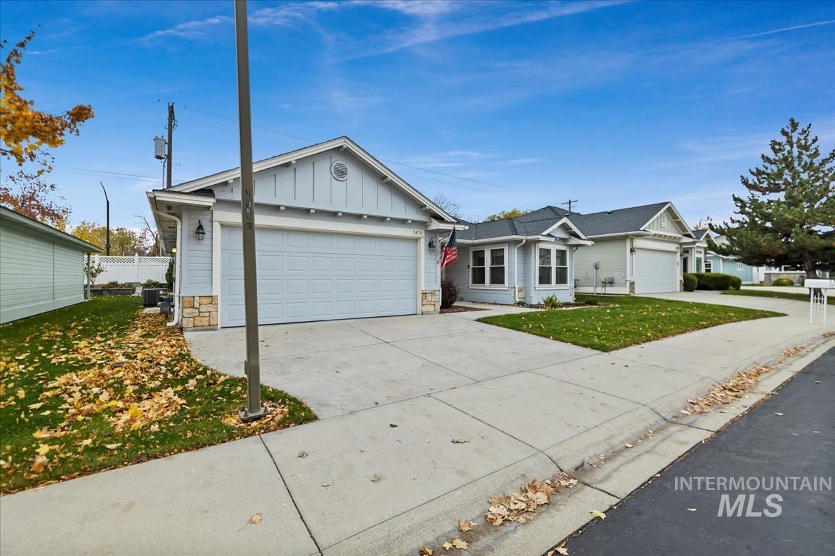 Ranch-style home featuring board and batten siding, stone siding, concrete driveway, and an attached garage