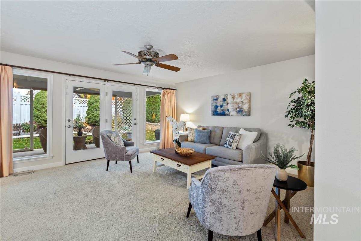 Living room featuring french doors, light carpet, and a ceiling fan