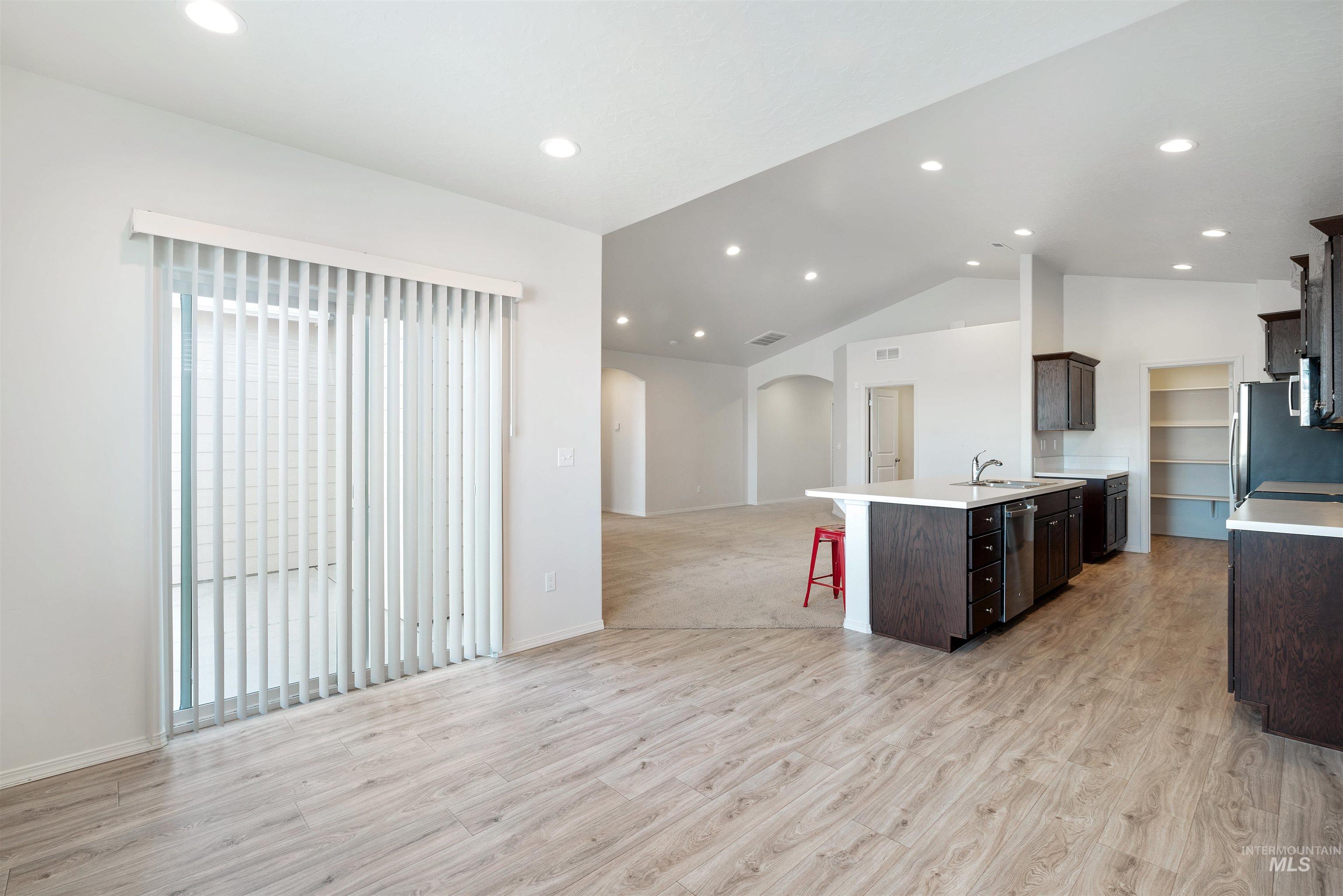 Kitchen featuring a breakfast bar area, open floor plan, vaulted ceiling, light wood-type flooring, and arched walkways