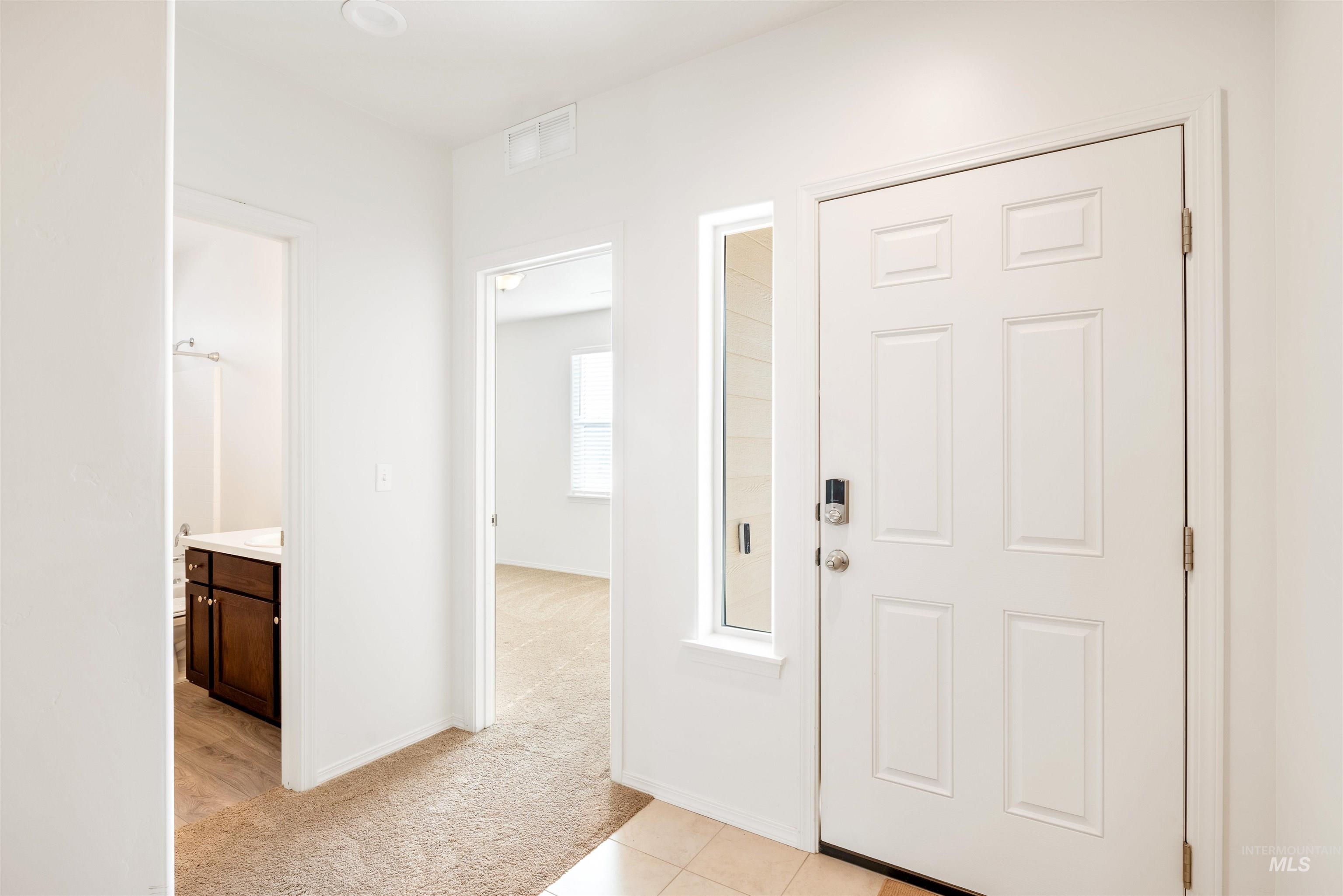 Entryway featuring light carpet and light tile patterned floors