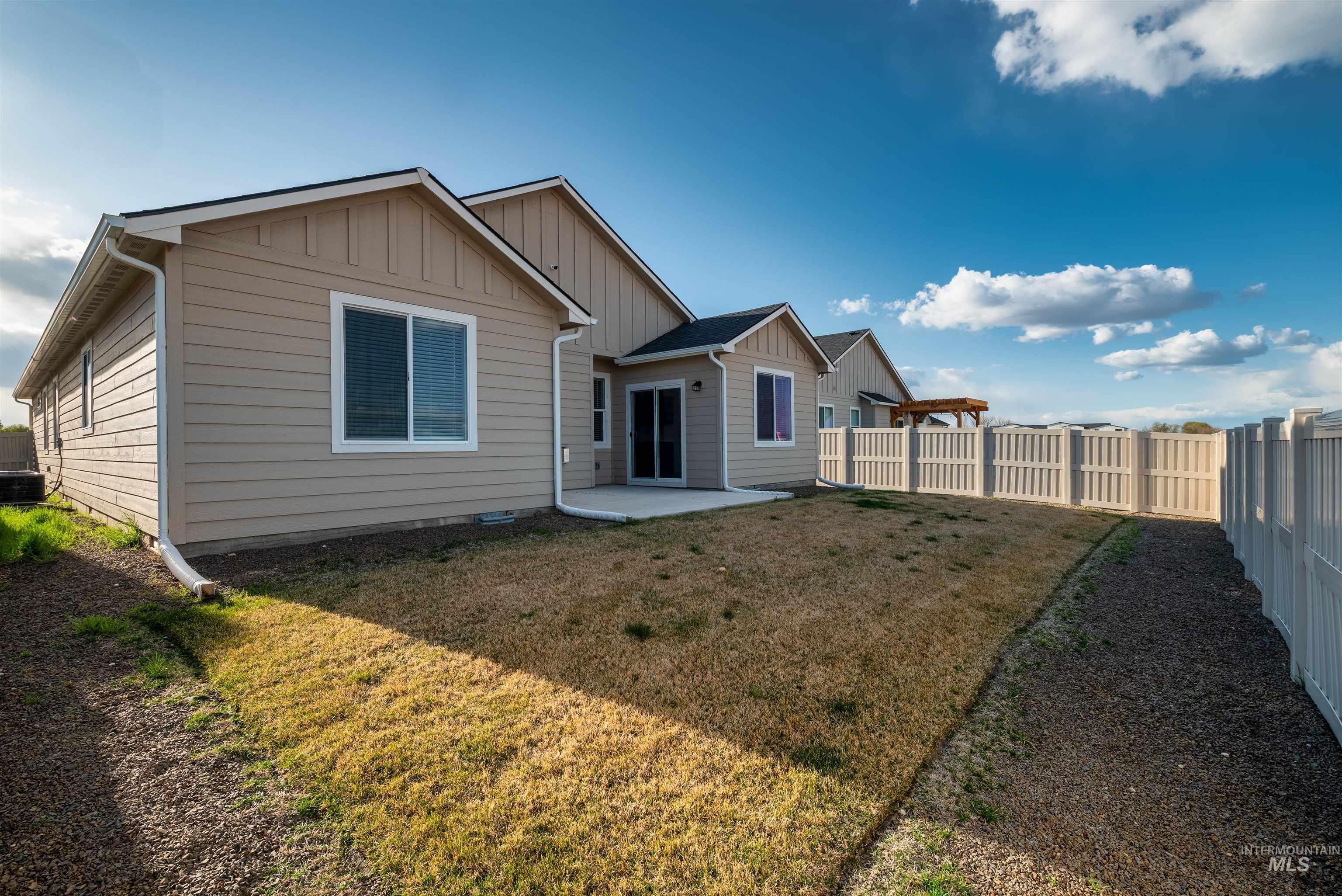 Rear view of house featuring a patio area, board and batten siding, and a fenced backyard