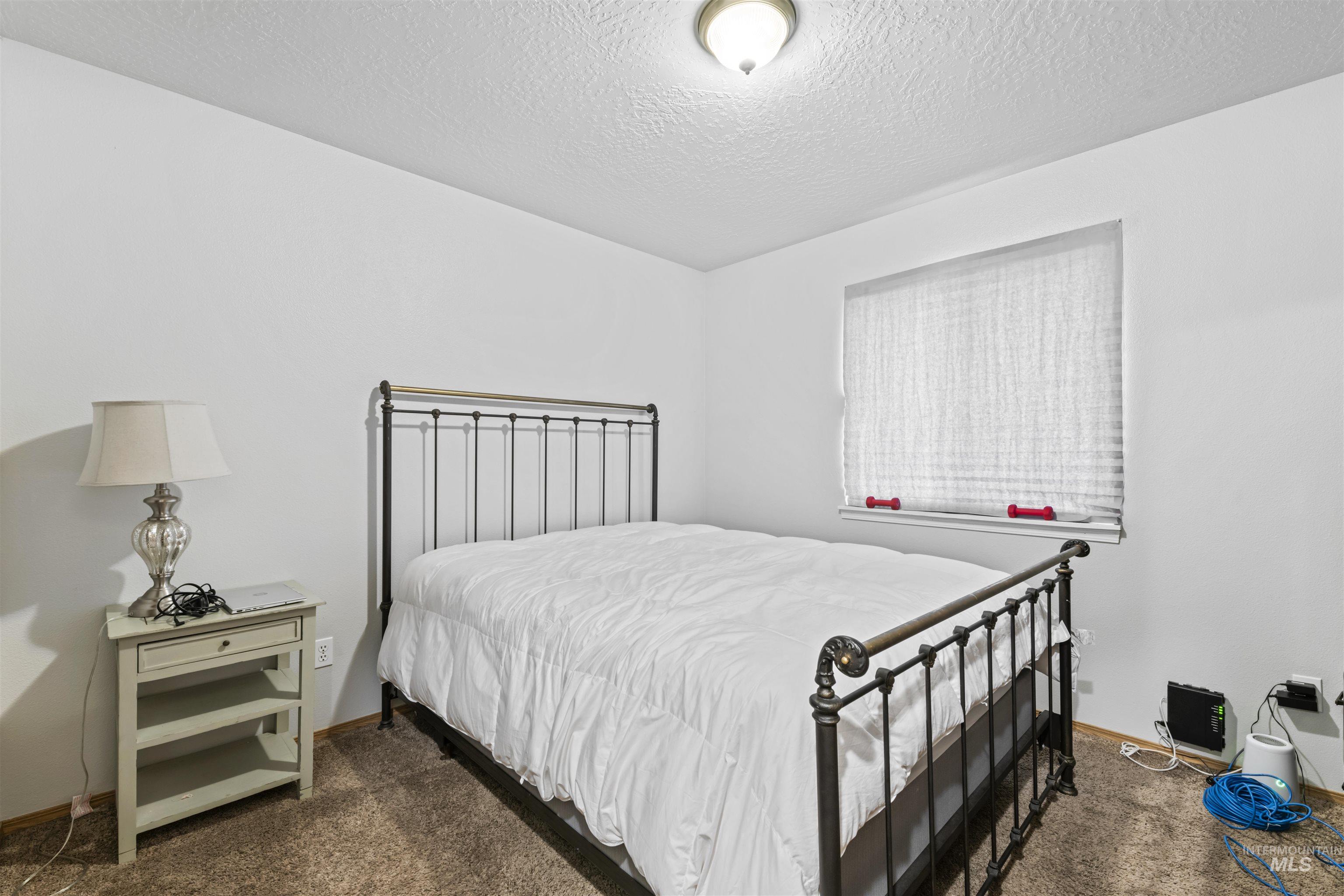 Bedroom with dark carpet and a textured ceiling