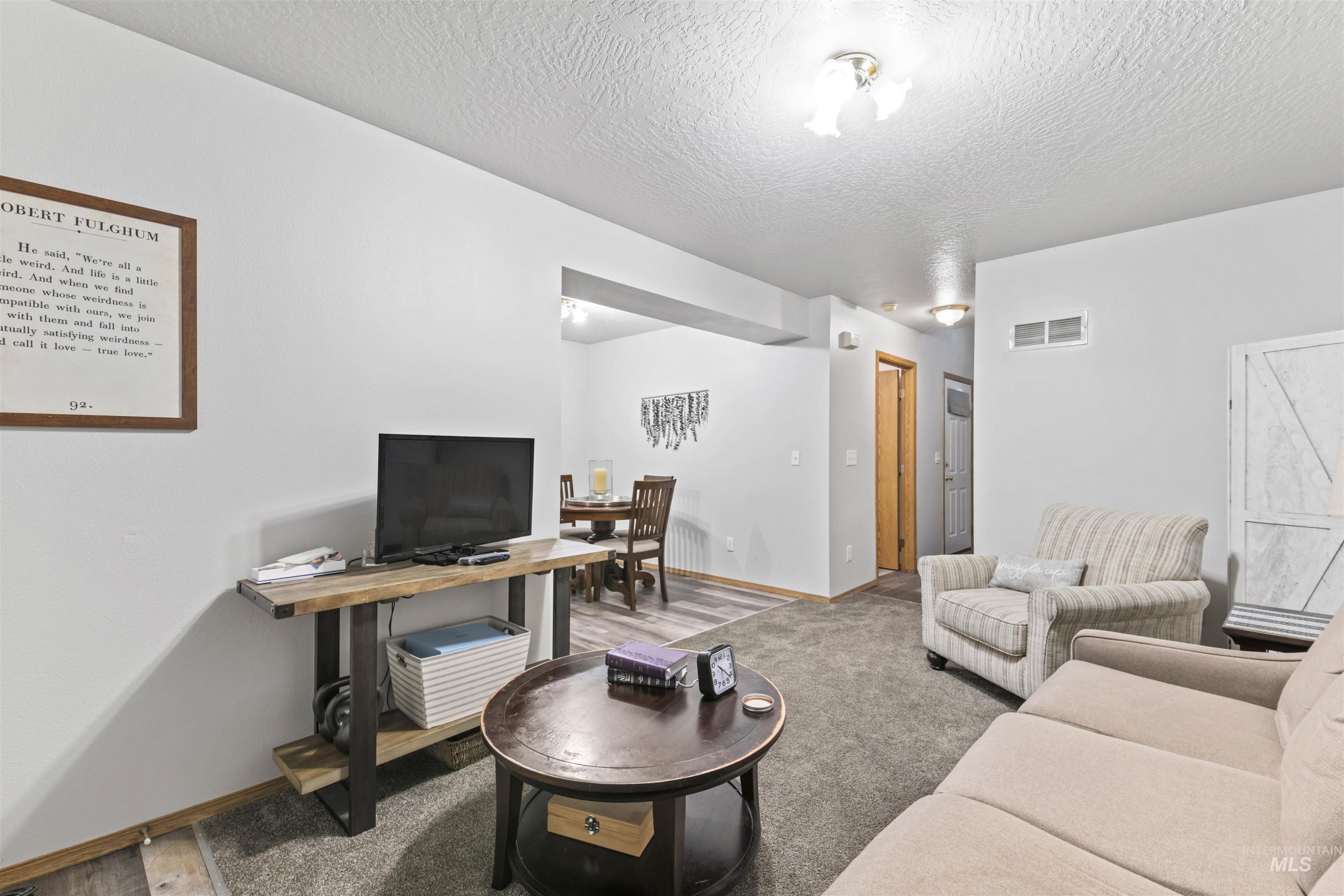 Carpeted living room with baseboards and a textured ceiling