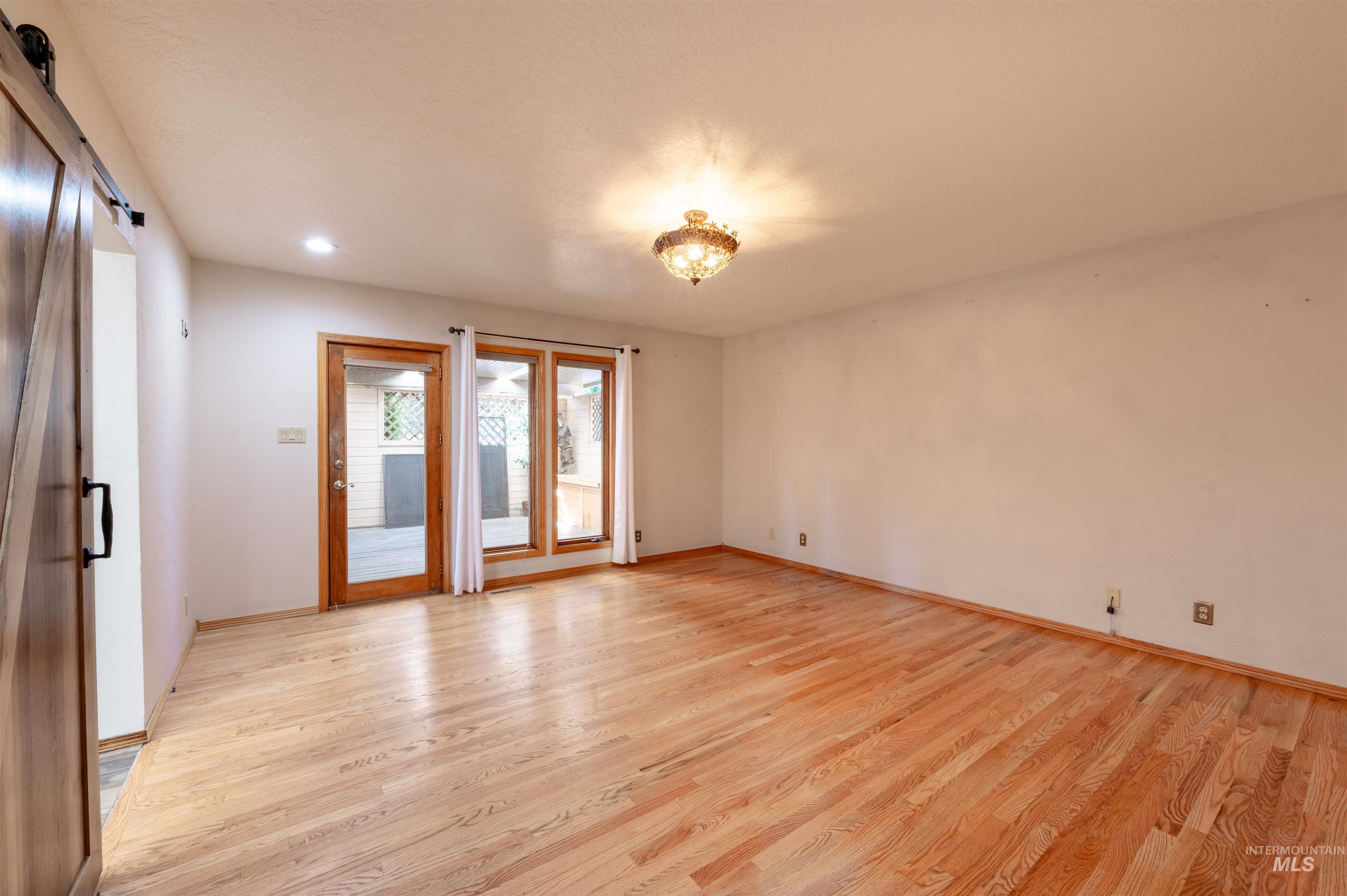 Spare room featuring a barn door, light wood-style flooring, and recessed lighting