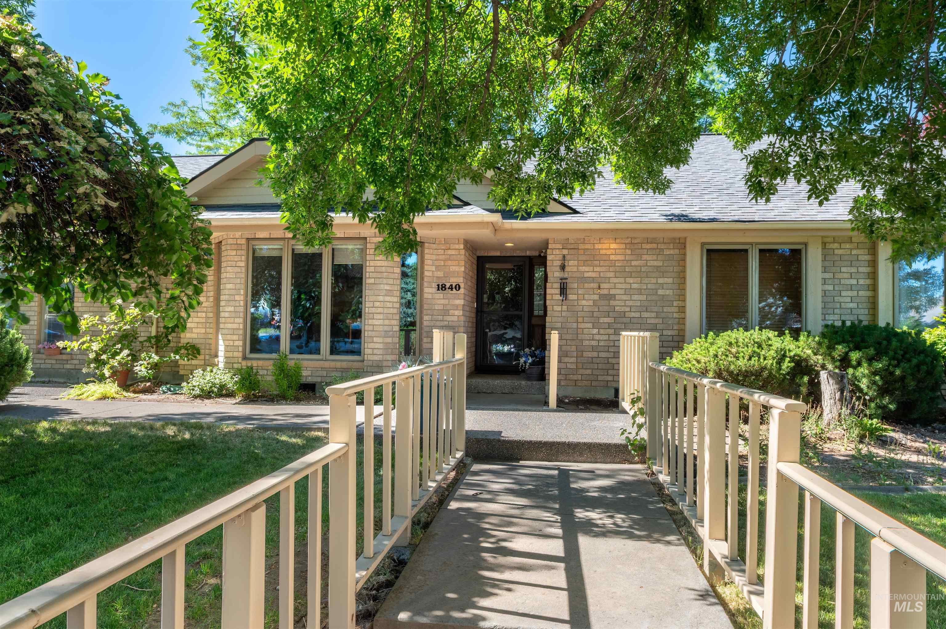 View of front of home featuring brick siding, a shingled roof, a front lawn, and a porch