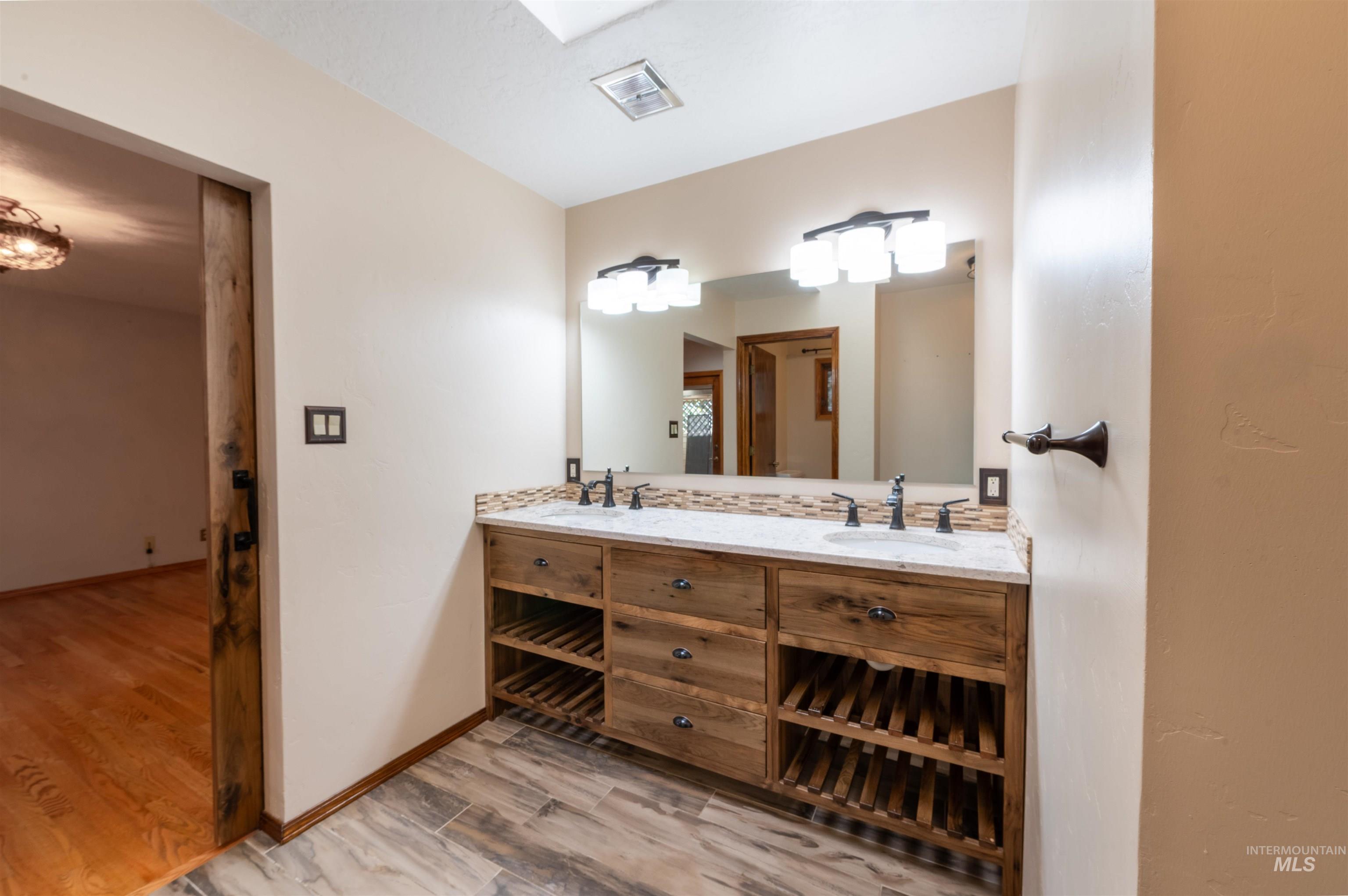 Full bathroom with light wood-type flooring and double vanity