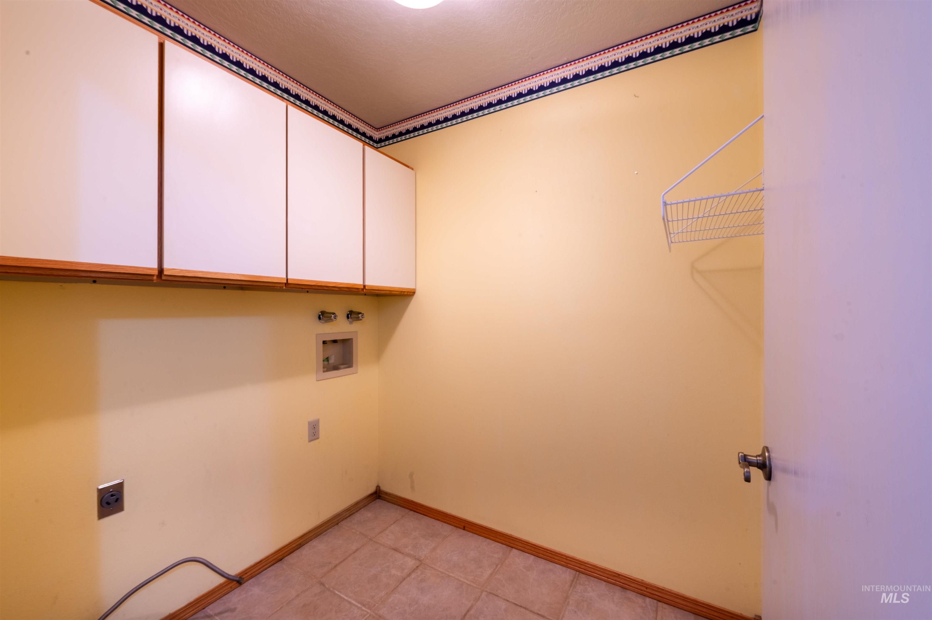 Laundry room with cabinet space, washer hookup, electric dryer hookup, and light tile patterned flooring