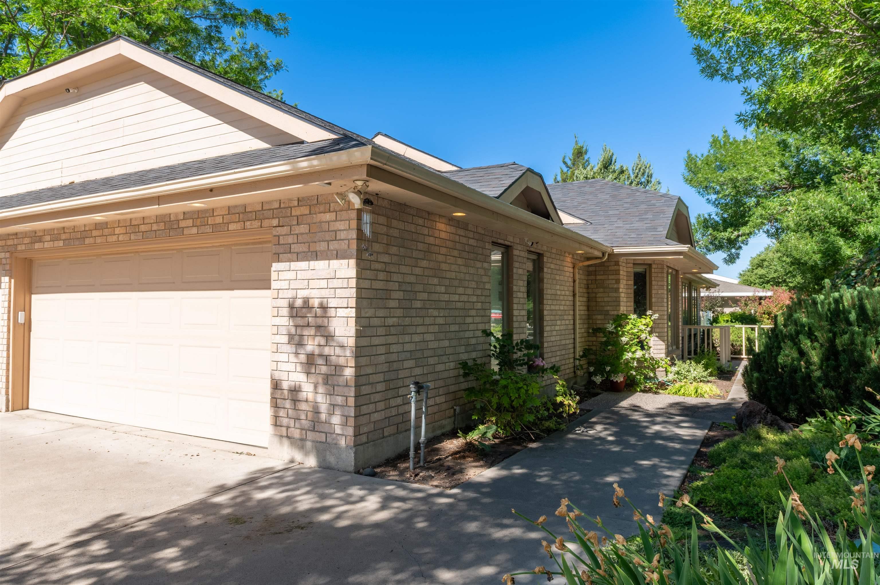 View of side of home featuring a shingled roof, driveway, and a garage