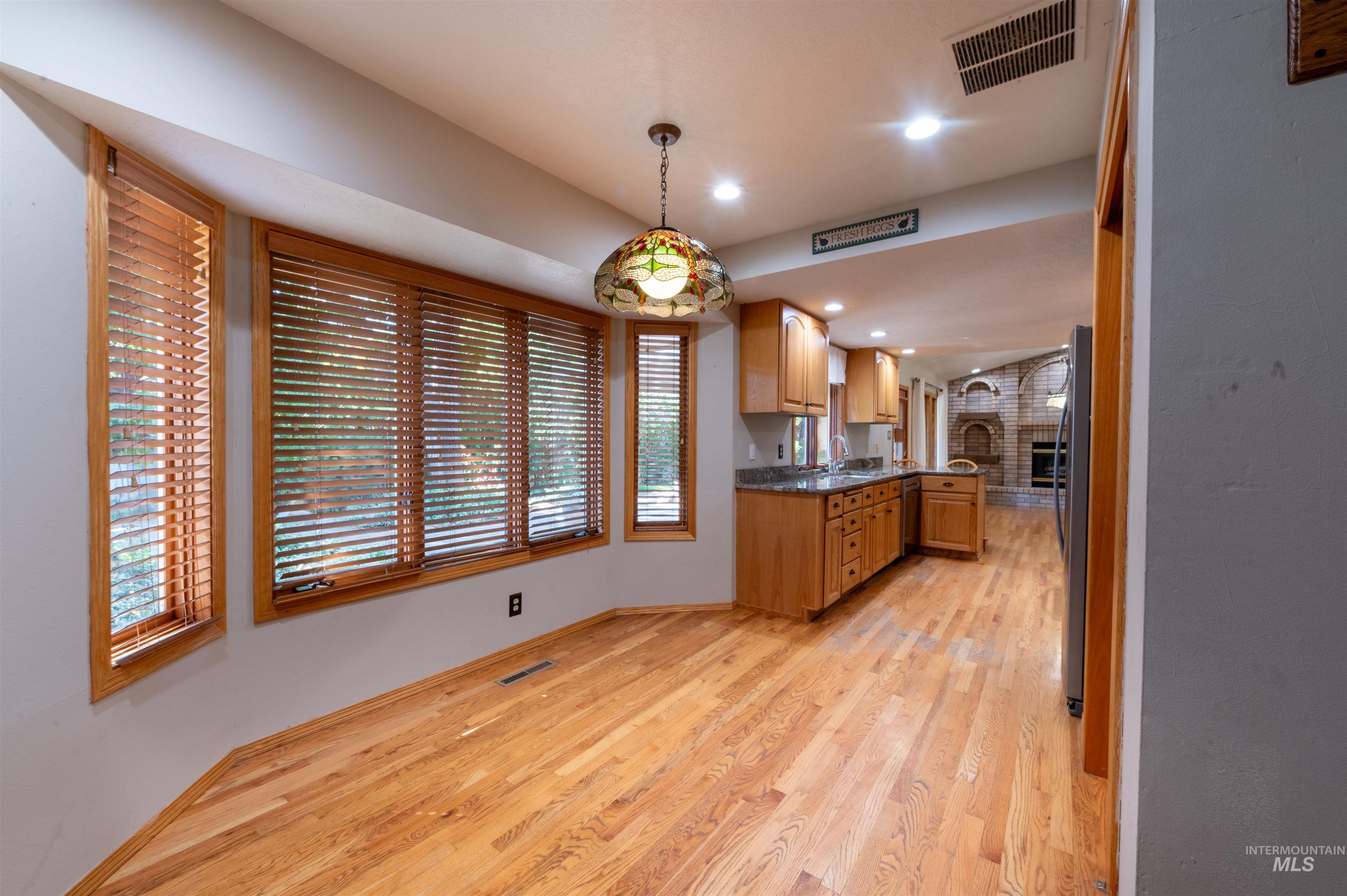Kitchen featuring light wood-style flooring, decorative light fixtures, a peninsula, recessed lighting, and fridge