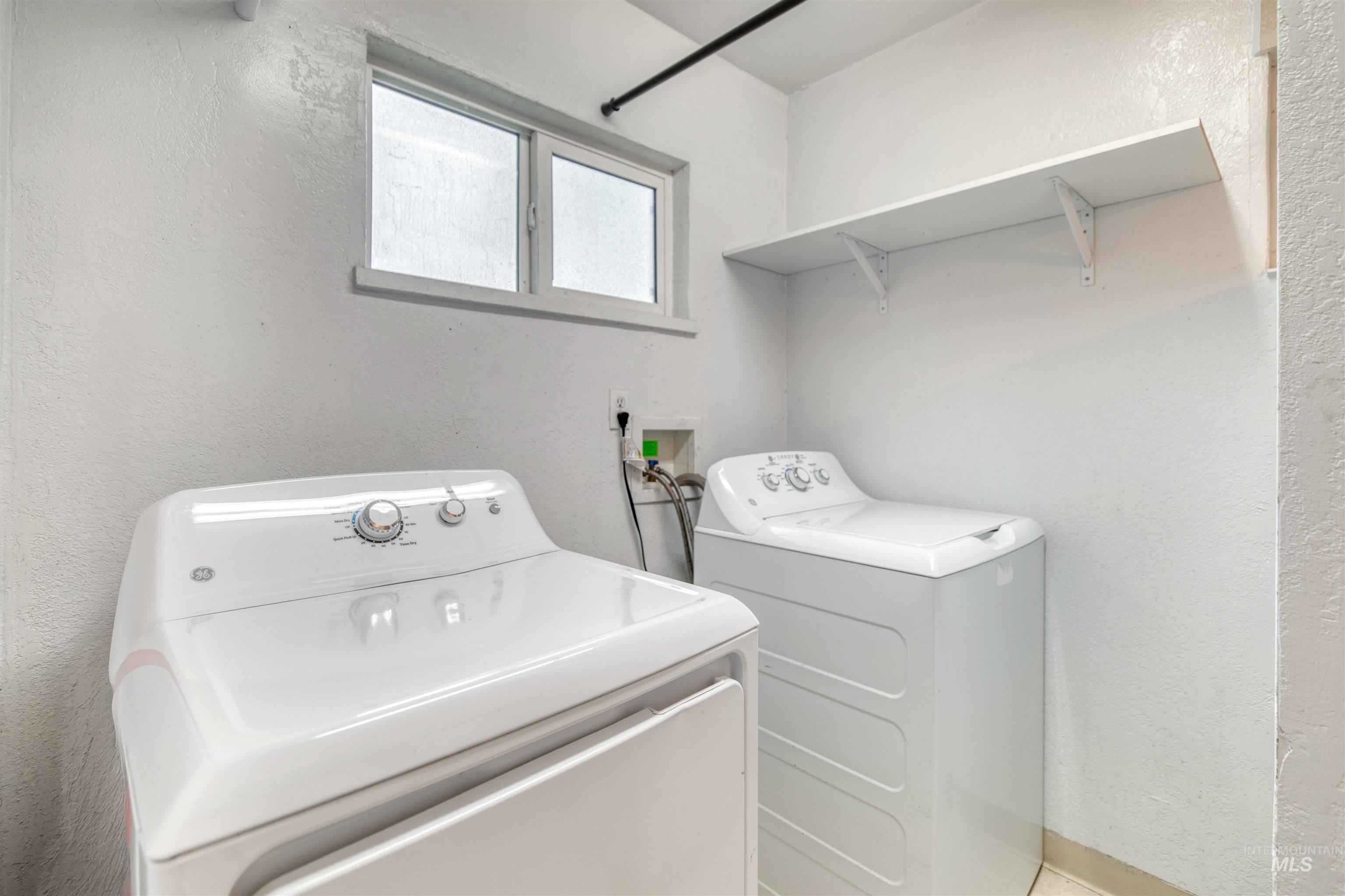 Laundry room with a textured wall and independent washer and dryer