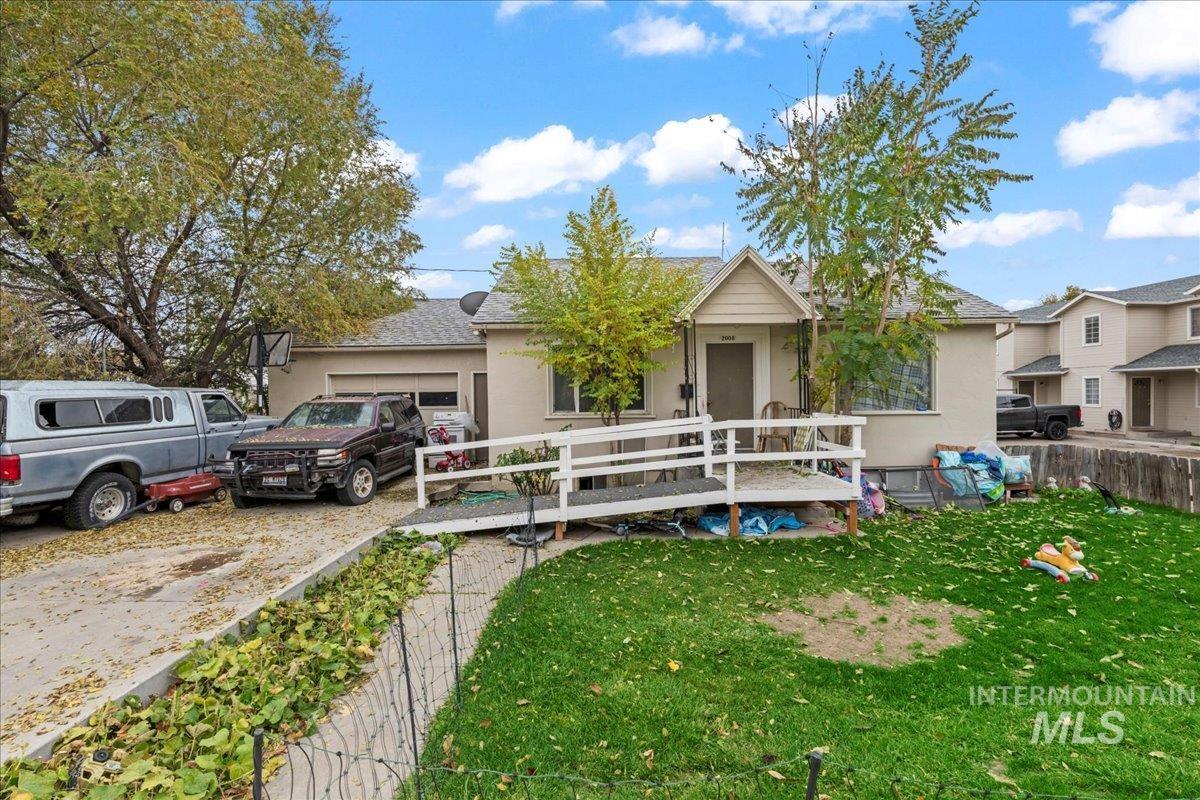 Ranch-style house featuring an attached garage, a deck, driveway, and stucco siding