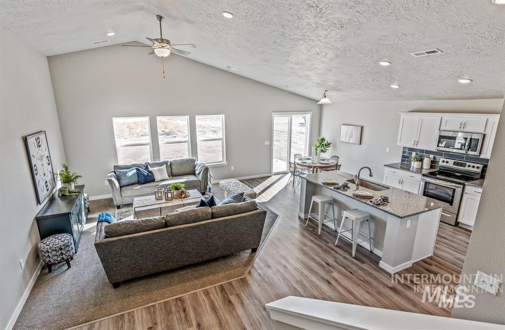 Living room featuring a textured ceiling, light wood-style flooring, high vaulted ceiling, recessed lighting, and ceiling fan