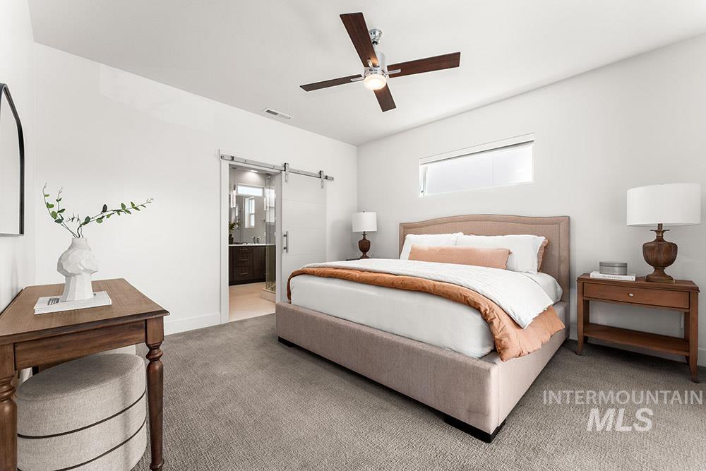 Bedroom with a barn door, carpet flooring, ensuite bathroom, and a ceiling fan