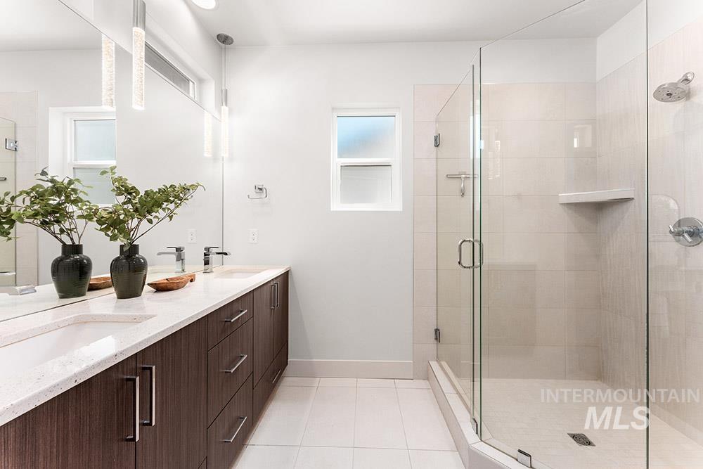 Bathroom with light tile patterned floors, double vanity, and a shower stall
