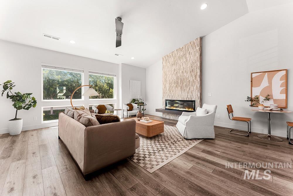 Living area with vaulted ceiling, light wood finished floors, a fireplace, and recessed lighting