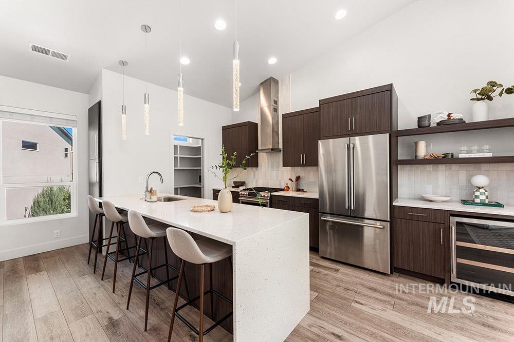 Kitchen featuring dark brown cabinets, modern cabinets, appliances with stainless steel finishes, a kitchen bar, and pendant lighting