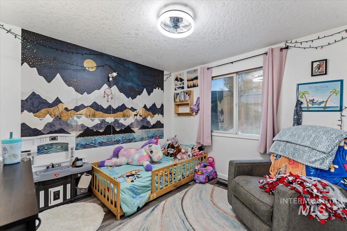 Bedroom with a textured ceiling and wood finished floors