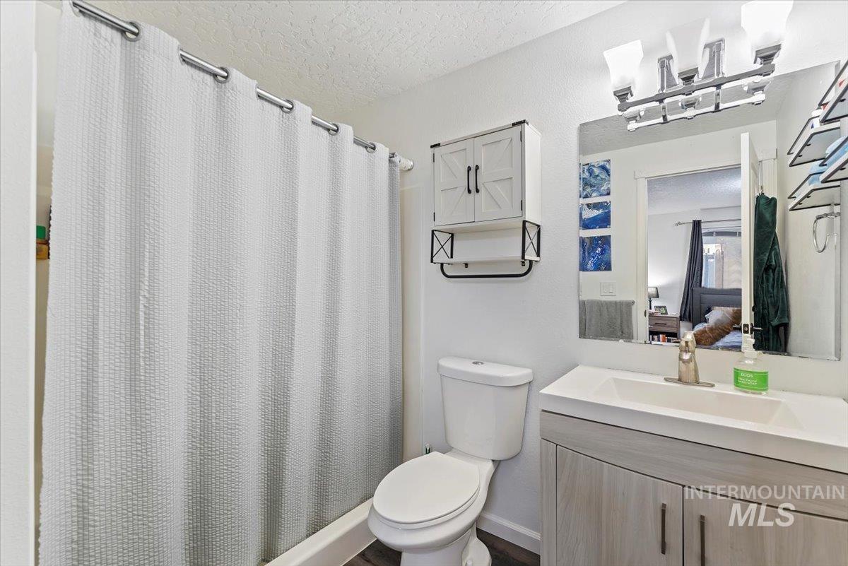 Ensuite bathroom with a shower stall, vanity, and a textured ceiling