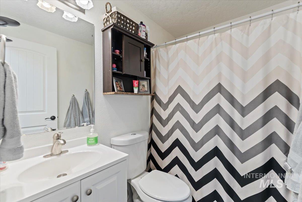 Bathroom featuring a textured ceiling, curtained shower, and vanity