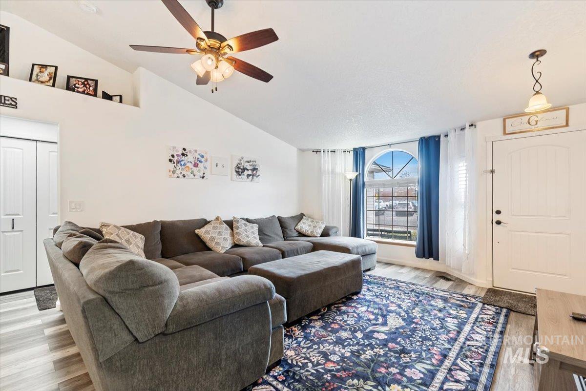 Living area featuring wood finished floors, a ceiling fan, and high vaulted ceiling