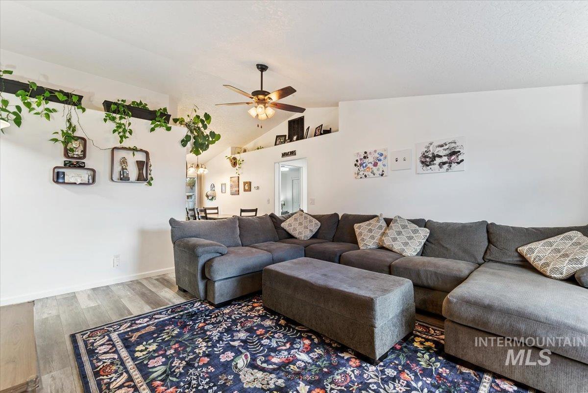Living room with lofted ceiling, wood finished floors, and ceiling fan