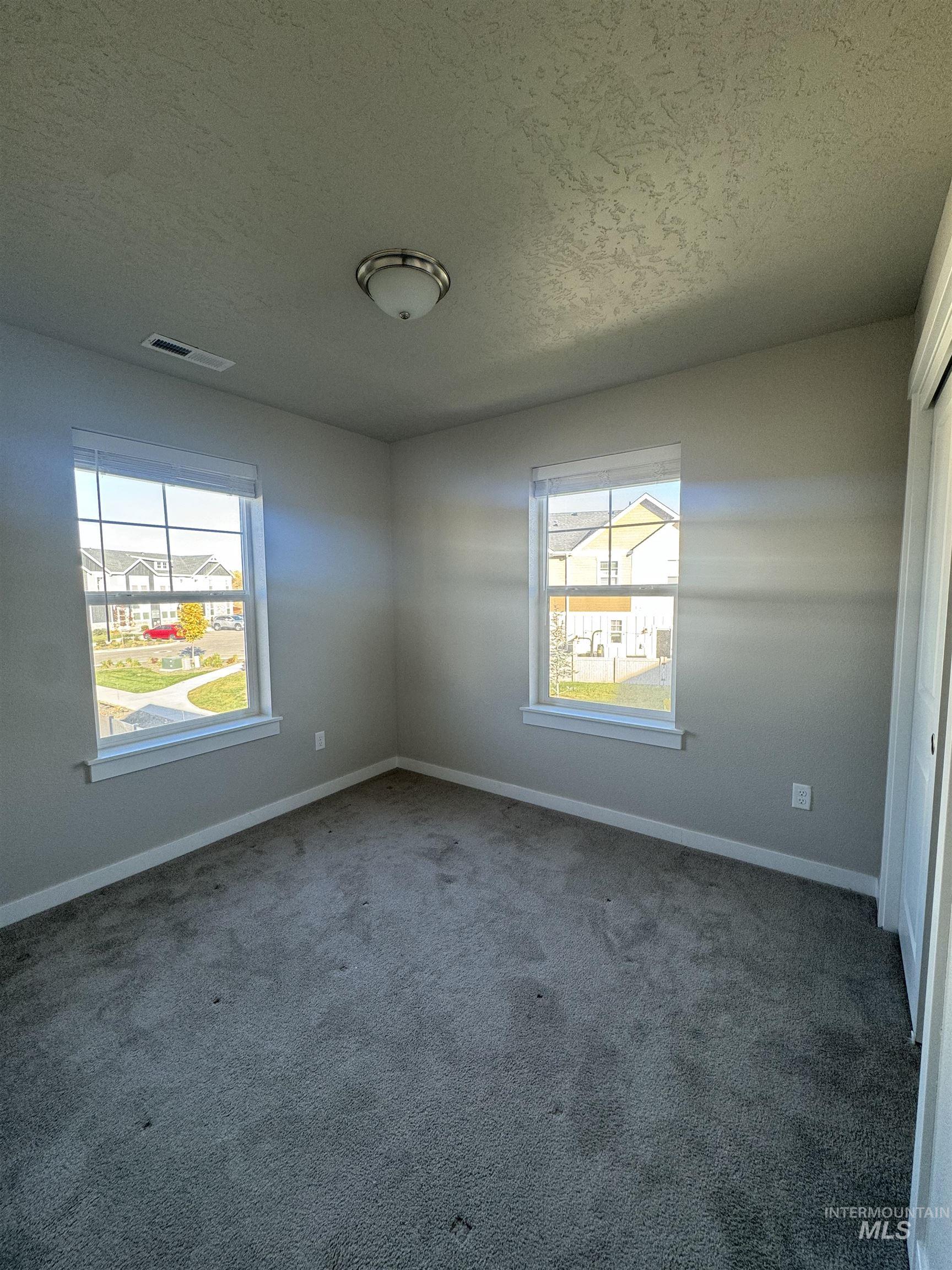 Carpeted spare room with a textured ceiling and plenty of natural light