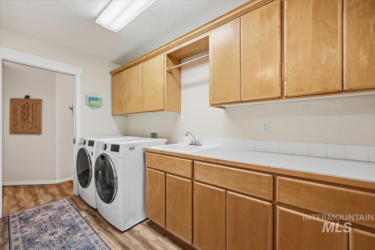 Washroom with light wood-type flooring, cabinet space, and washing machine and dryer