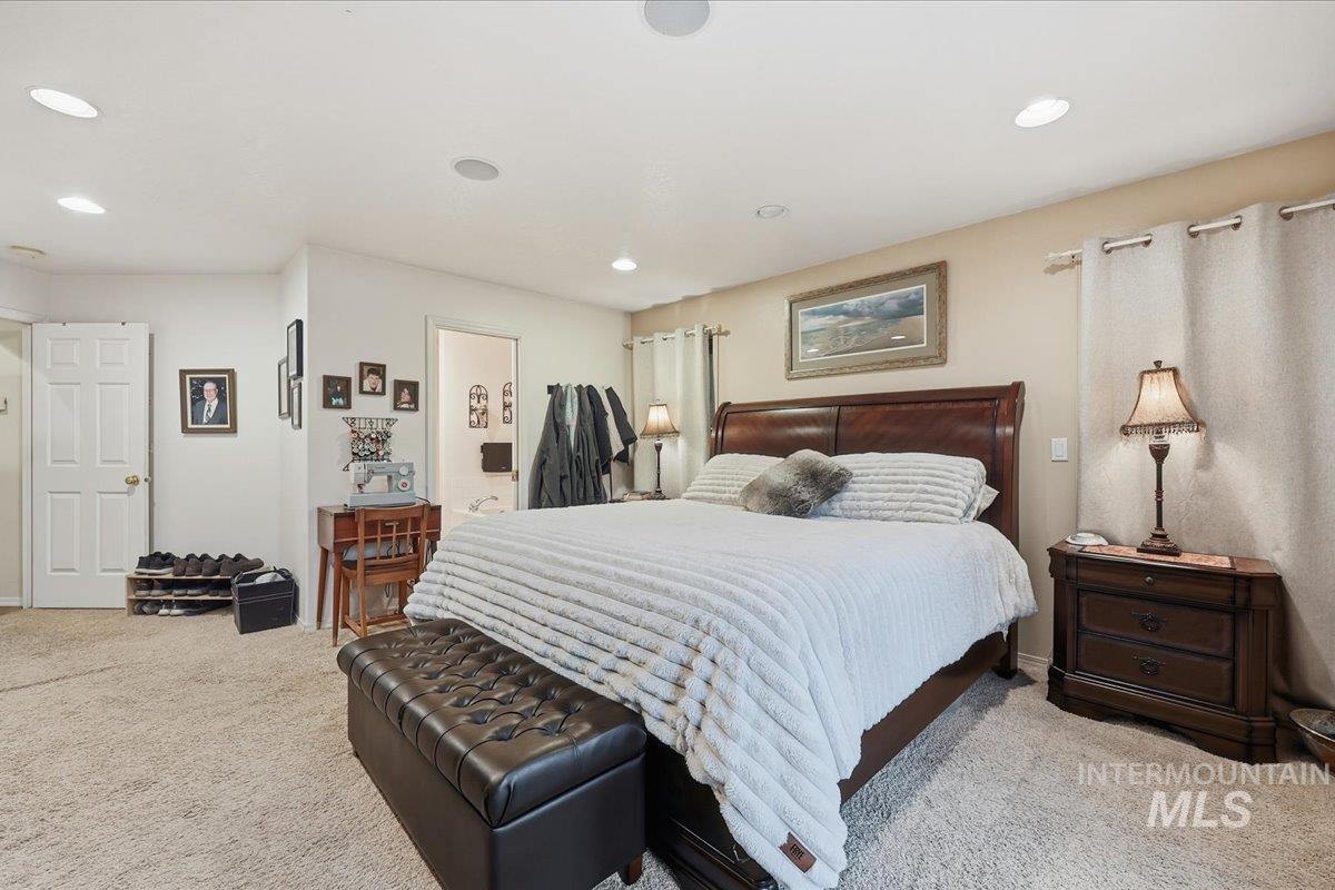 Bedroom featuring light colored carpet, recessed lighting, and ensuite bath