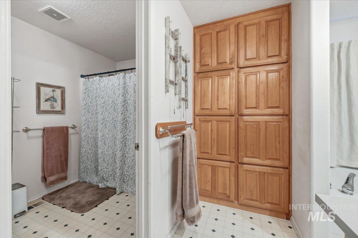Full bathroom featuring a stall shower, a textured ceiling, and light flooring