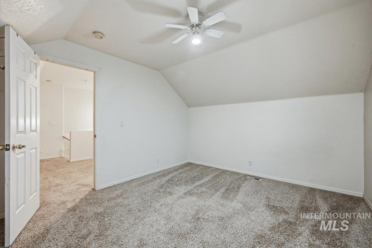 Additional living space featuring vaulted ceiling, carpet floors, and a ceiling fan