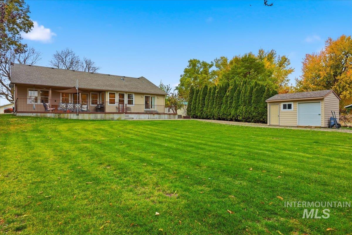 Rear view of house with a lawn, a garage, and a storage shed