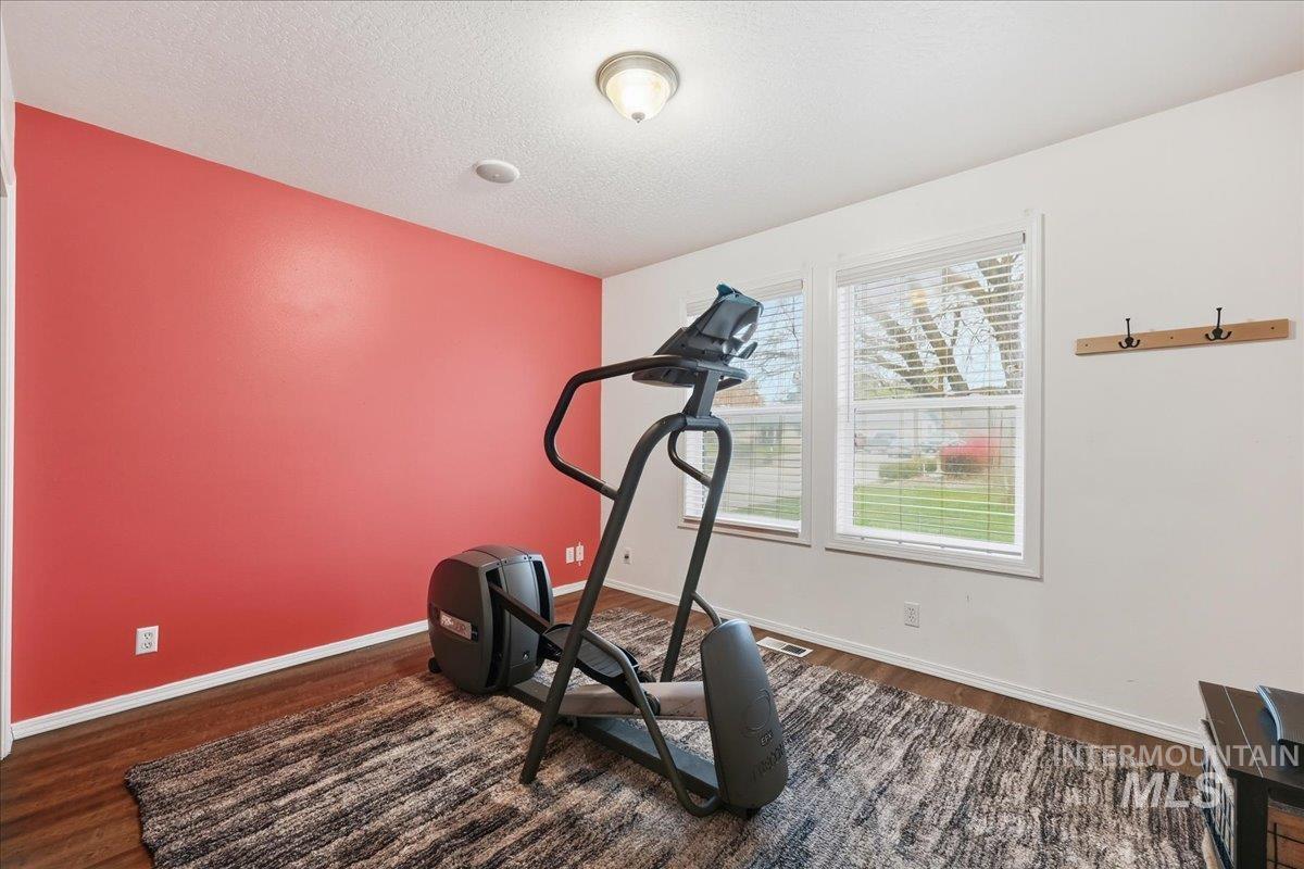 Exercise area with dark wood-style flooring and a textured ceiling