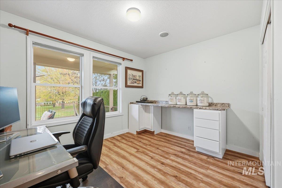 Home office featuring light wood-style flooring and a textured ceiling