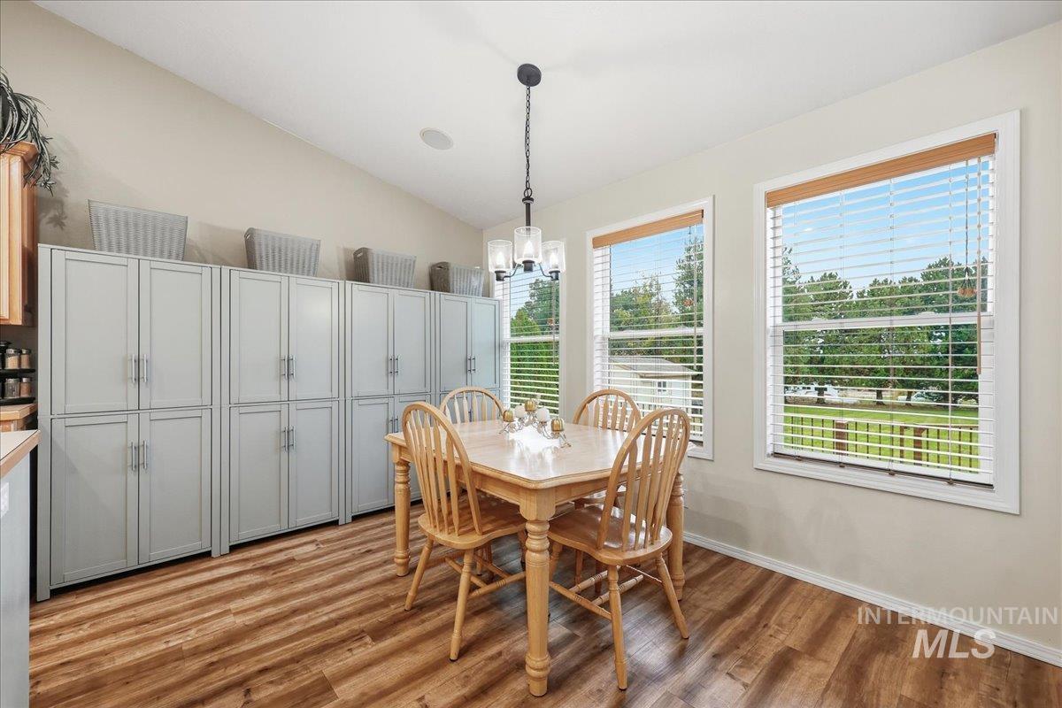 Dining area with vaulted ceiling, light wood-type flooring, and a chandelier