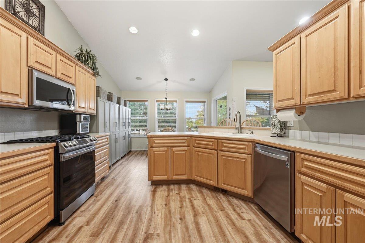 Kitchen featuring stainless steel appliances, light wood-type flooring, decorative light fixtures, light countertops, and recessed lighting