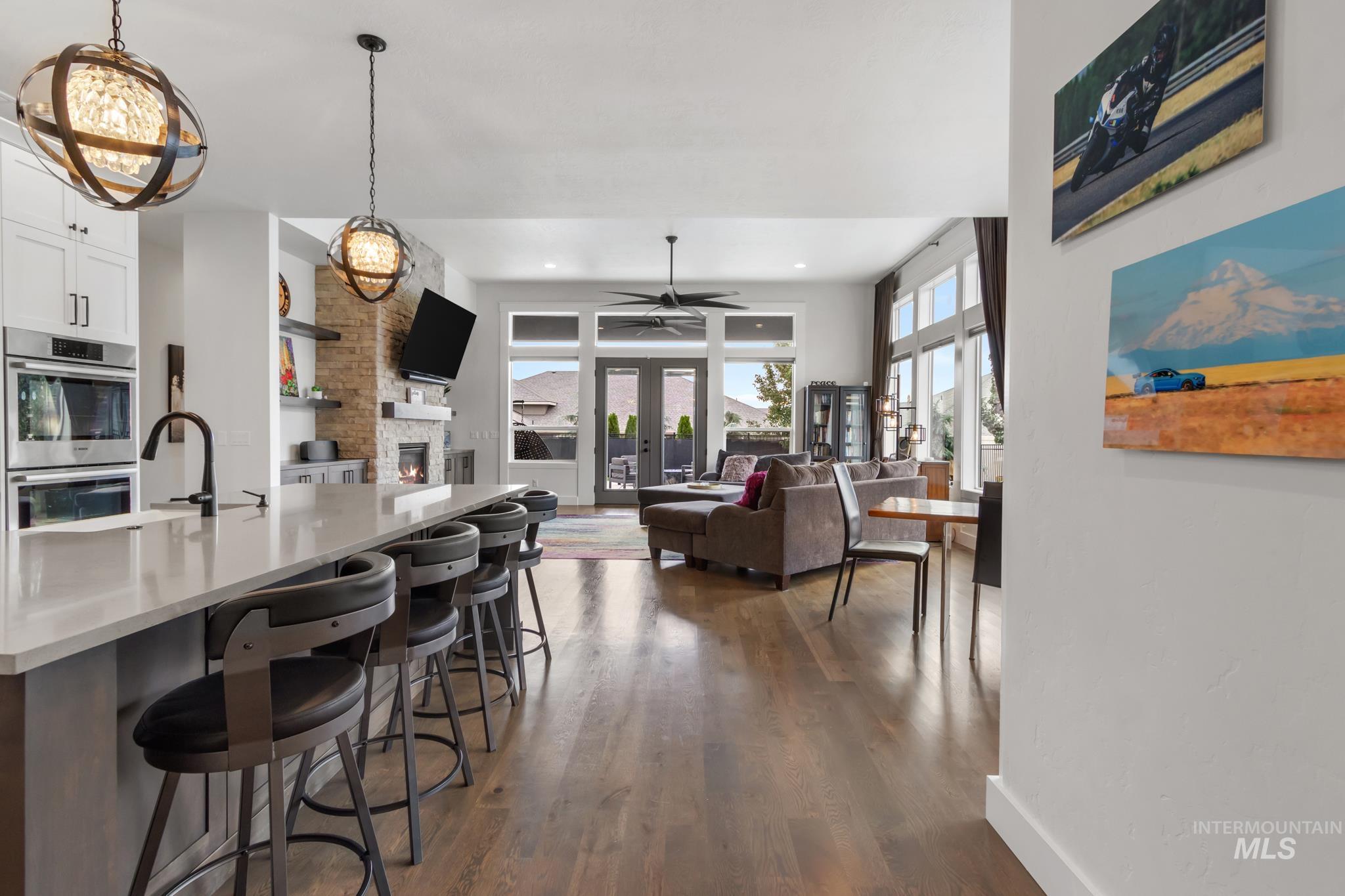 Kitchen featuring dark wood-style flooring, a fireplace, hanging light fixtures, double oven, and a breakfast bar