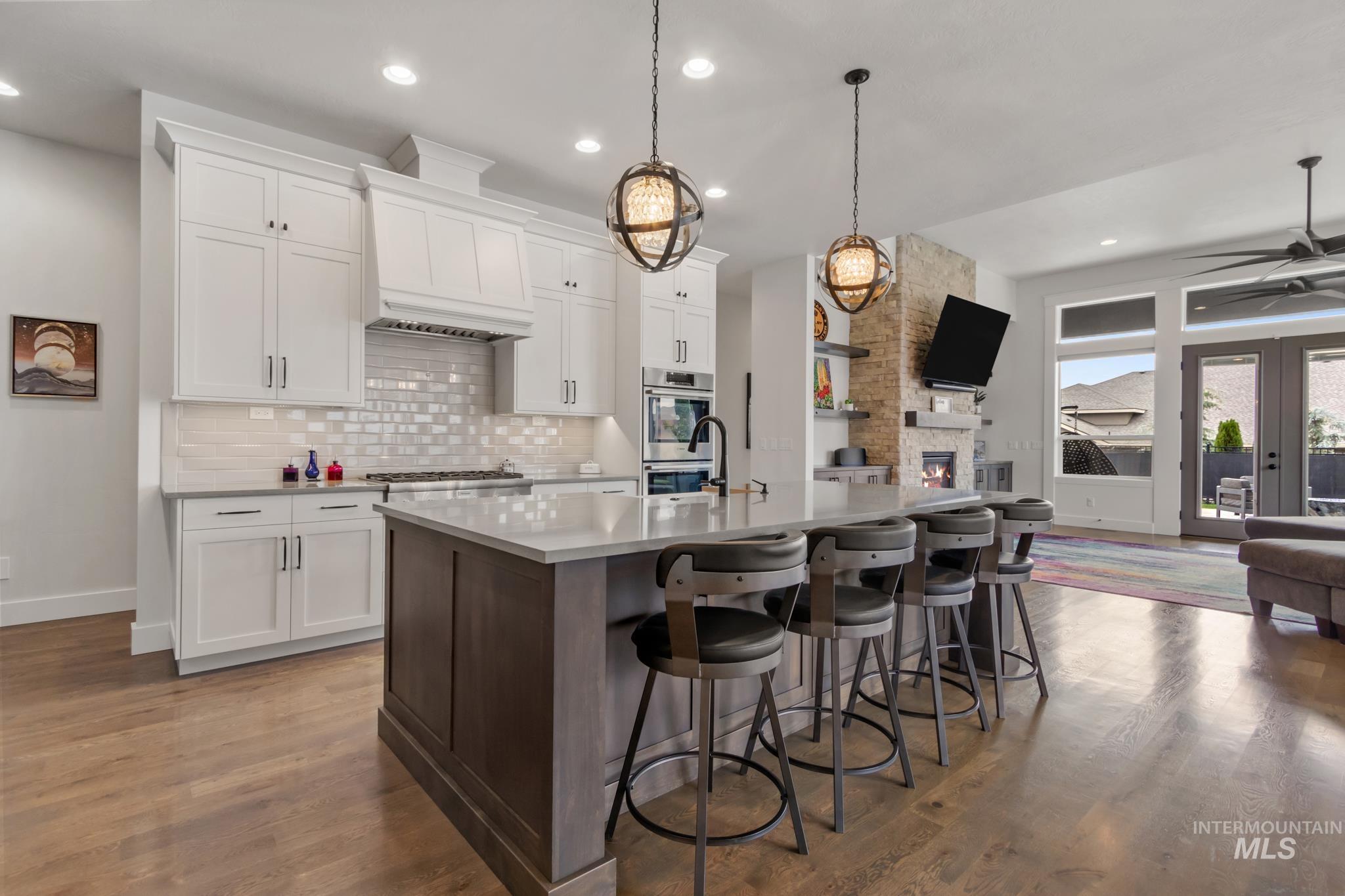 Kitchen with dark brown cabinetry, open floor plan, a kitchen bar, white cabinetry, and decorative backsplash