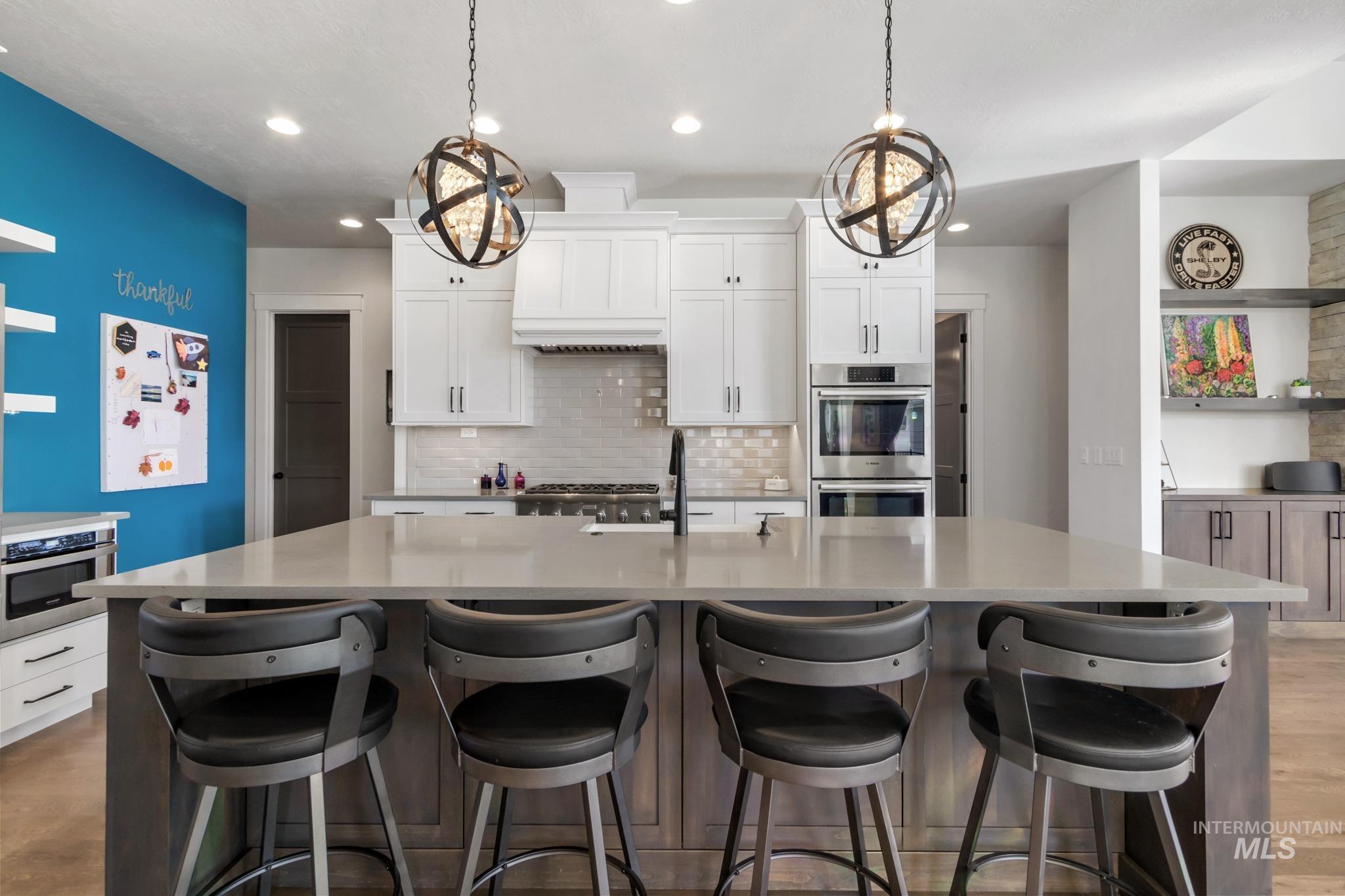 Kitchen featuring white cabinetry, dark wood-type flooring, backsplash, a center island with sink, and recessed lighting