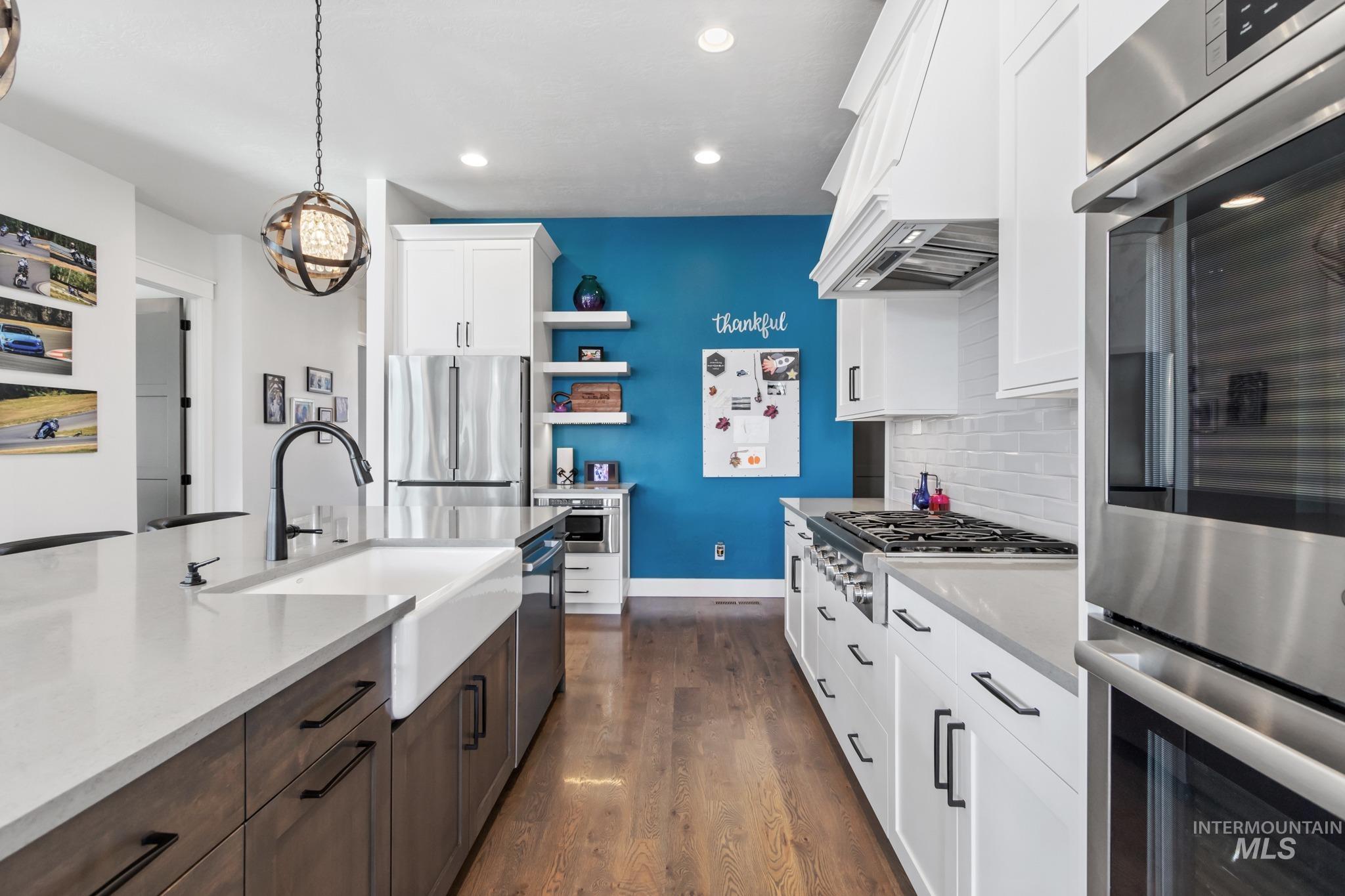 Kitchen with appliances with stainless steel finishes, dark wood-style flooring, open shelves, premium range hood, and decorative backsplash