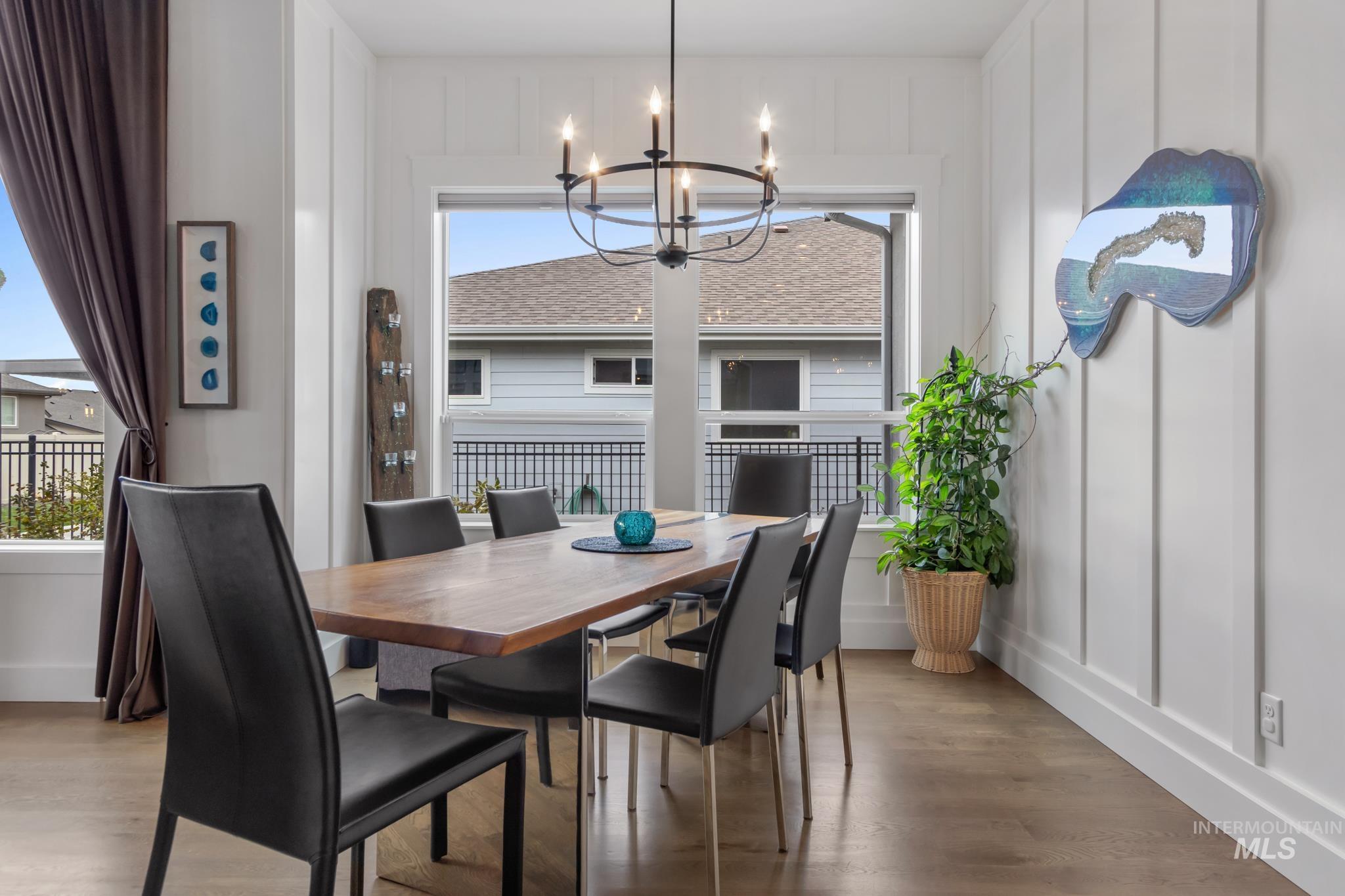Dining area with a decorative wall, wood finished floors, and a chandelier