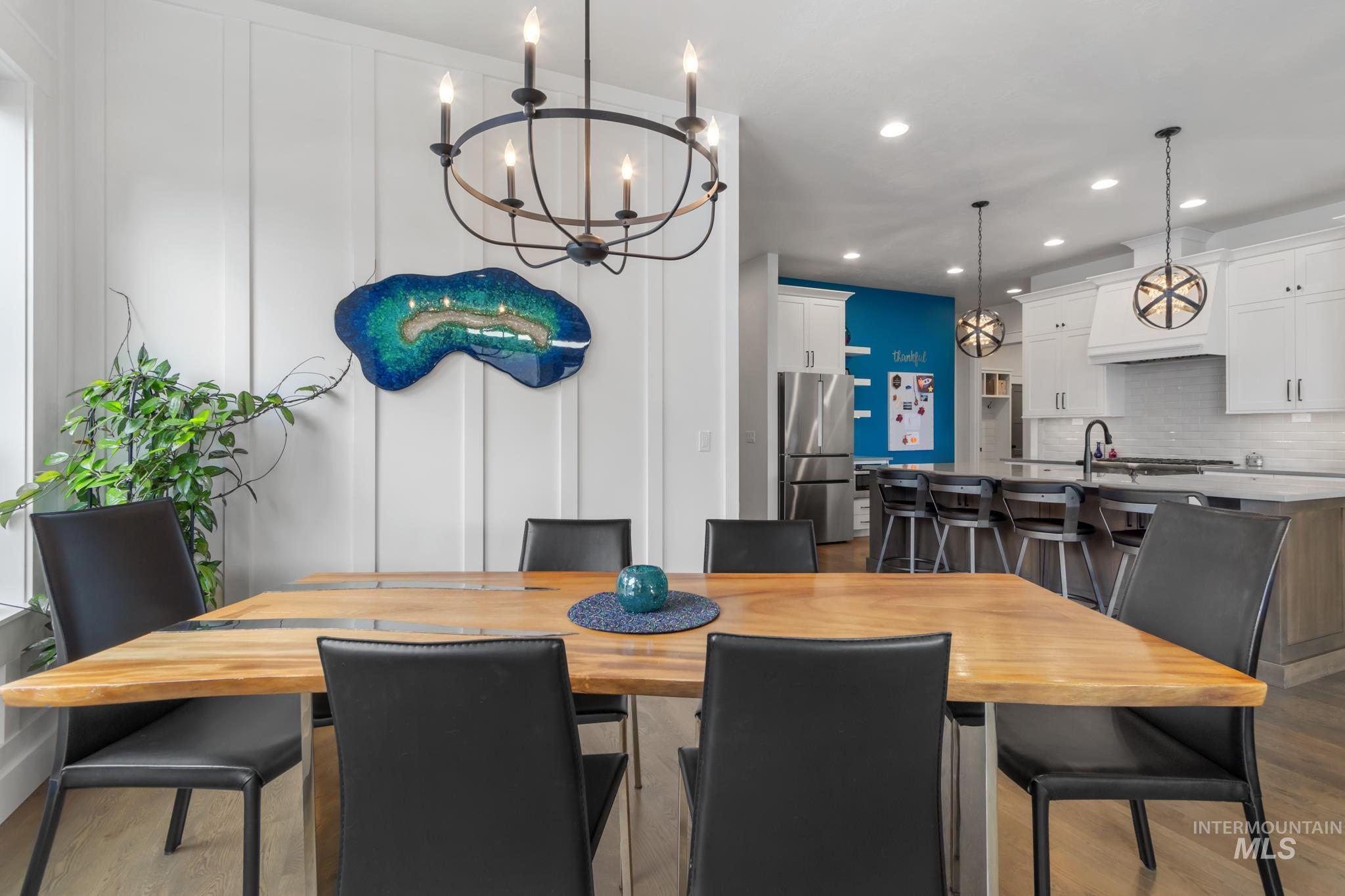 Dining area with light wood finished floors, recessed lighting, a decorative wall, and a chandelier